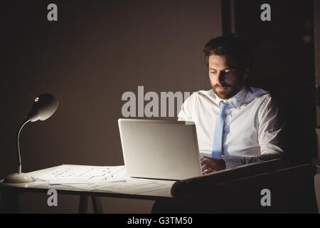 Businessman using laptop at night Banque D'Images