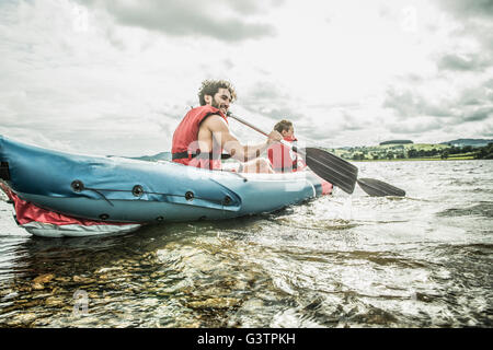 Un homme et un garçon dans un kayak à la rive, sur le lac Bala au Pays de Galles. Banque D'Images