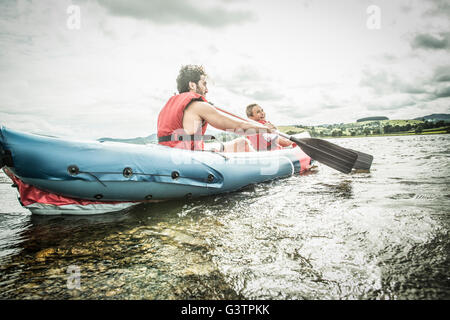 Un homme et un garçon dans un kayak à la rive, sur le lac Bala au Pays de Galles. Banque D'Images