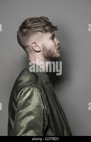 Studio portrait d'un jeune homme barbu portant un blouson vert. Banque D'Images