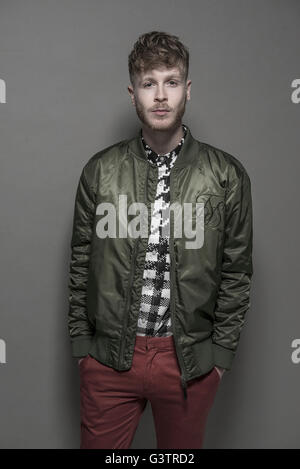 Studio portrait d'un jeune homme barbu portant un blouson vert. Banque D'Images