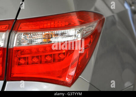 Détail de phare arrière rouge voiture gris avec reflets. Banque D'Images