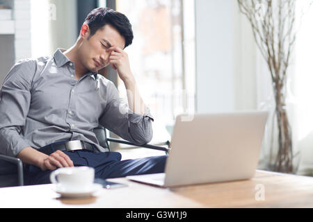 Jeune homme fatigué se frotter les yeux dans office Banque D'Images
