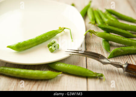 Gousse de pois verts et la fourche sur la plaque blanche. Banque D'Images