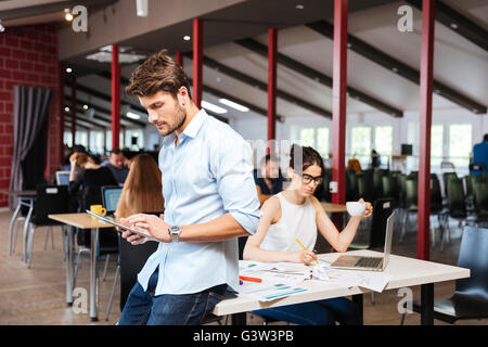 Jeune homme concentré et de travail à l'aide de tablet in office Banque D'Images