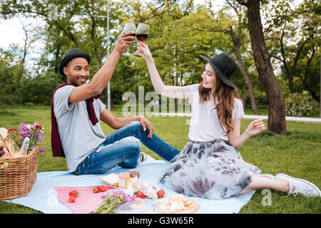 Cheerful young couple drinking wine on picnic in park Banque D'Images