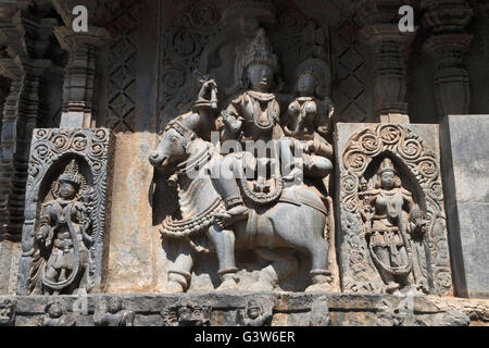 Sculptures sur la façade, côté ouest murs. shiva-parvati assis sur nandi. hoysaleshwara temple, halebidu, Karnataka, Inde. Banque D'Images