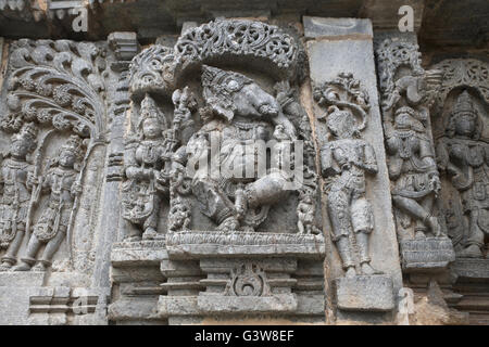 Panneau mural bas-reliefs représentant (de gauche), son épouse Kamdev Rati et danse Ganesha. Kedareshwara temple, Halebidu, Inde Banque D'Images