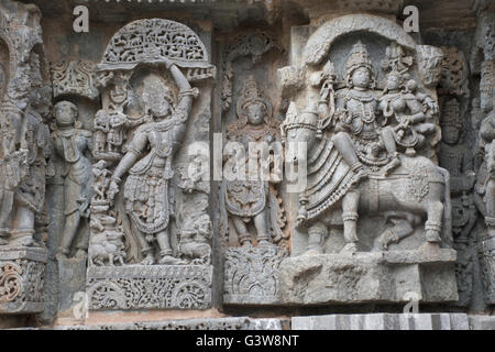 Panneau mural bas-reliefs représentant (de gauche) Krishna , Shiva-Parvati assis sur Nandi, Kedareshwara, temple Halebid, Karnataka, Inde Banque D'Images