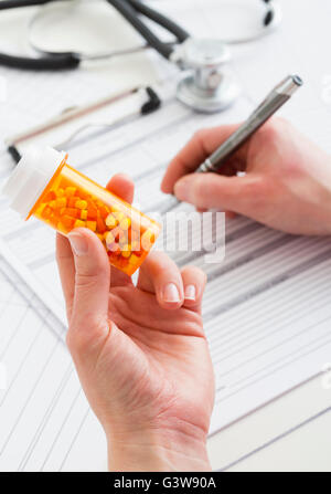 Doctor holding pill bottle et documents de remplissage Banque D'Images