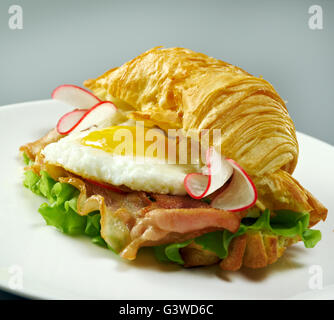 Matin d'été Petit-déjeuner Croissant fourré des œufs brouillés et bacon frit Banque D'Images