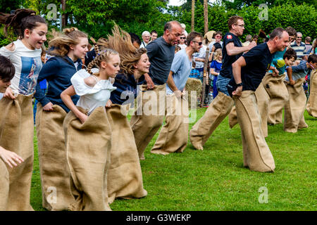 Adolescents et adultes, dans un sac de course à la course traditionnelle foire médiévale de Abinger, Surrey, UK Banque D'Images