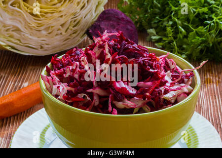 Salade de betteraves, de l'alimentation avec la carotte, le chou, l'huile d'olive et citron. Servi dans un bol sur fond de bois. Banque D'Images