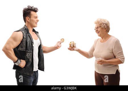 Punk Rocker en tenant les cookies d'un senior lady isolé sur fond blanc Banque D'Images