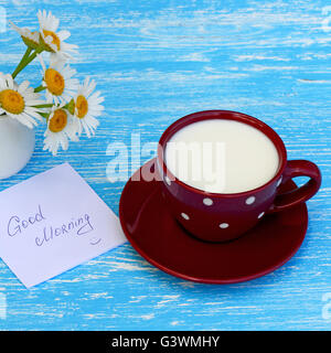 Fleurs Daisy et tasse de lait avec un bon matin note sur fond de bois bleu rustique Banque D'Images