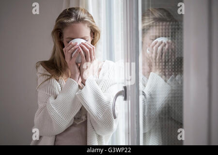 Jolie femme de boire le café du matin par la fenêtre Banque D'Images