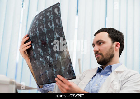 Closeup portrait of man intellectuelle avec le personnel des soins de santé, à la recherche de blanche labcoat cerveau x-ray image radiographie, tomodensitométrie, IRM, une clinique. Service de radiologie Banque D'Images