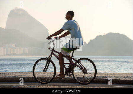 RIO DE JANEIRO - le 3 avril 2016 : Jeune homme brésilien monte un vélo sur la promenade à bord de la plage de Copacabana. Banque D'Images