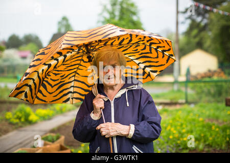 Femme âgée à l'extérieur debout sous un parapluie. Banque D'Images