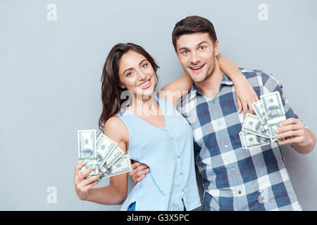 Happy young couple montrant leur argent isolé sur fond gris Banque D'Images