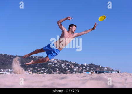 Garçon plonge pour attraper Frisbee. Boy est lancé pour capturer le frisbee sur la plage Banque D'Images