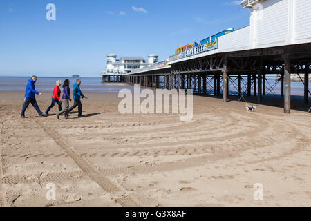 Les vacanciers à pied sur la plage avec un petit chien vers la grande jetée à Weston-Super-Mare. Banque D'Images