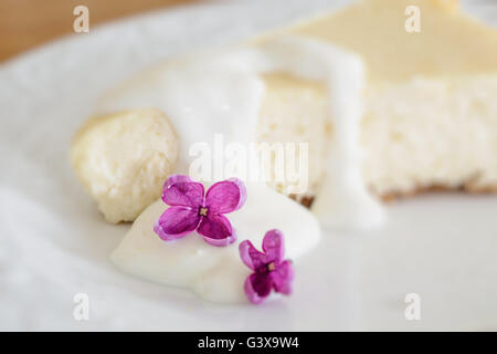 Cheesecake citron décoré avec des fleurs lilas. Profondeur de champ intentionnel avec l'accent sur la fleur de lilas. Banque D'Images