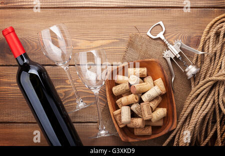 Bouteille de vin rouge, verres à vin, bol avec bouchons et tire-bouchon. Vue de dessus sur fond de table en bois rustique Banque D'Images