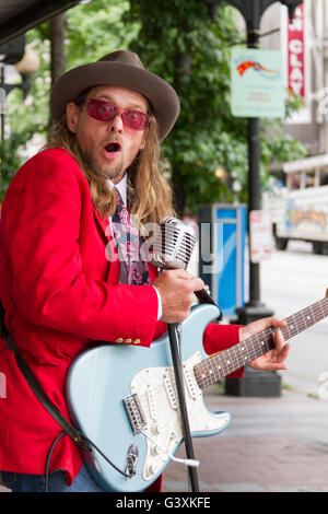 Un musicien de rue à Seattle dans une veste rouge qui joue de la guitare et à la peur Banque D'Images
