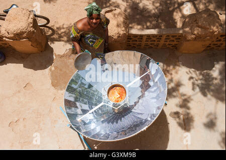 MALI Bandiagara, transition énergétique, la femme à la cuisinière solaire, un miroir parabolique, préparer la nourriture dans le village Banque D'Images