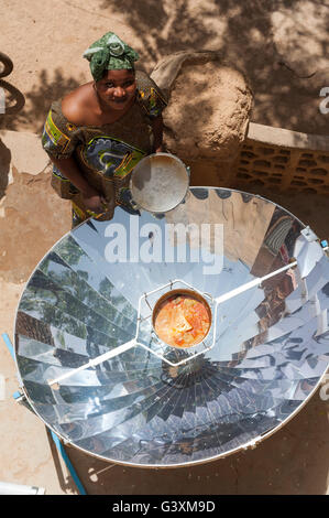 MALI Bandiagara, transition énergétique, la femme à la cuisinière solaire, un miroir parabolique, préparer la nourriture dans le village Banque D'Images