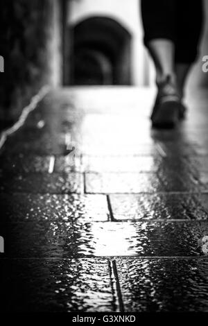 Marche sous la pluie sur le sol en pierre rustique en Italie en noir & blanc Banque D'Images