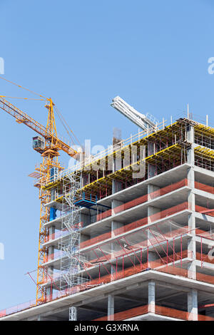 Site de construction d'immeubles d'appartements avec des grues contre le ciel bleu Banque D'Images