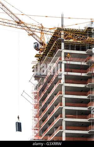 Site de construction en béton avec des grues à tour contre ciel nuageux Banque D'Images