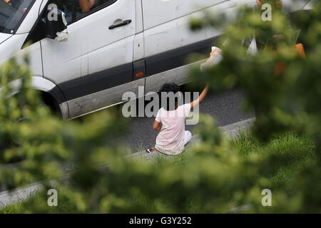 Paris, France. 16 Juin, 2016. Une femme donne du pain à la mendicité d'une jeune fille dans une rue animée de Saint-Denis près de Paris, France, le 16 juin 2016. Photo : CHRISTIAN CHARISIUS/dpa/Alamy Live News Banque D'Images