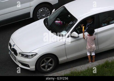 Paris, France. 16 Juin, 2016. Un pilote donne une banane à une jeune fille mendier dans une rue animée de Saint-Denis près de Paris, France, le 16 juin 2016. Photo : CHRISTIAN CHARISIUS/dpa/Alamy Live News Banque D'Images