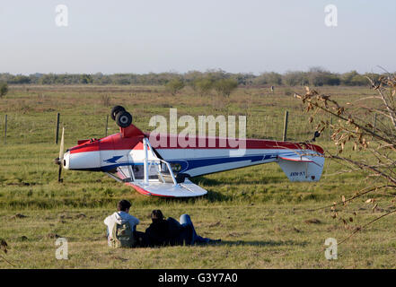 Buenos Aires, Argentine. 16 Juin, 2016. Les gens s'asseoir à côté d'un avion léger renversé près de l'autoroute La Plata-Buenos Aires dans la province de Buenos Aires, Argentine, le 16 juin 2016. L'accident s'est produit après l'échec de moteur d'avion, avec le pilote et son compagnon indemnes. Crédit : Carlos Cermele/TELAM/Xinhua/Alamy Live News Banque D'Images