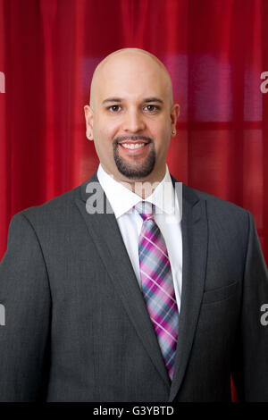 Portrait d'un groom dans un costume gris et cravate rose et gris. Il a une barbe de menton. Banque D'Images