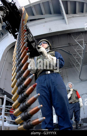 Gunner's Mate Seaman en tenant sur un but de calibre 50 fusil sur une cible flottante à bord du USS Ronald Reagan. Banque D'Images