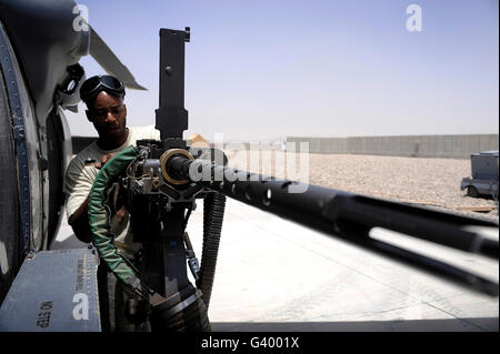 U.S. Air Force Airman opération de maintenance de routine sur la mitrailleuse de calibre .50 d'un HH-60G Pave Hawk. Banque D'Images