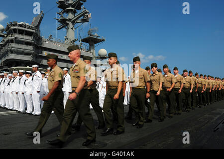 Les Marines américains marcher en formation à mettre en place à l'homme les rails avec les marins à bord de l'USS Ronald Reagan. Banque D'Images