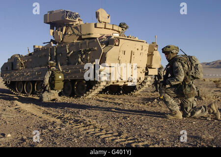 Les soldats de l'armée américaine d'assurer la sécurité d'un véhicule de combat Bradley M2. Banque D'Images