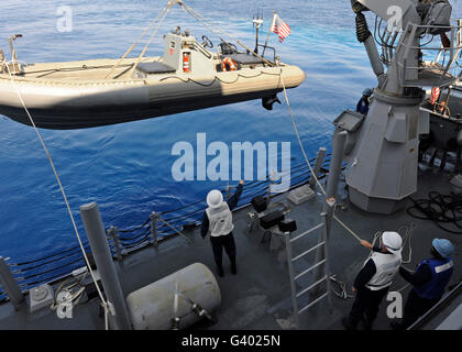 Abaisser les marins une embarcation pneumatique à coque rigide à l'eau. Banque D'Images