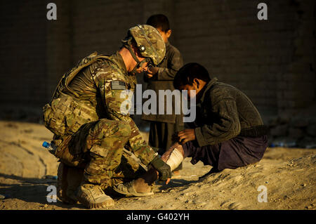 Airman fournit une aide médicale à un Afghan garçon. Banque D'Images