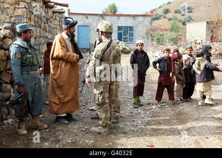 Soldat de l'armée américaine et d'un uniforme de policier afghan parle avec un village officiel. Banque D'Images