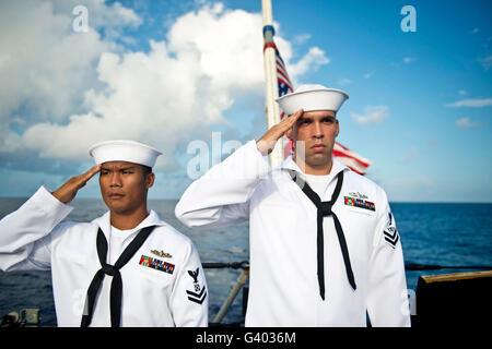 Les marins rendre un salut de la main au cours d'un enterrement en mer la cérémonie. Banque D'Images