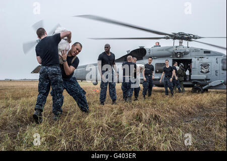 Charge les marins des approvisionnements de secours sur un Sea Hawk MH-60R hélicoptère. Banque D'Images