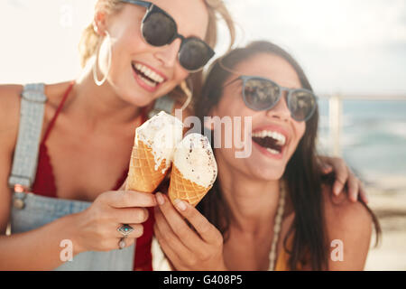 Deux jeunes amies s'amuser et de manger de la crème glacée. Cheerful young women eating icecream en plein air. Banque D'Images