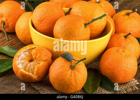 Les tangerines en jaune bol. Tangerines fraîches sur fond rustique. Banque D'Images