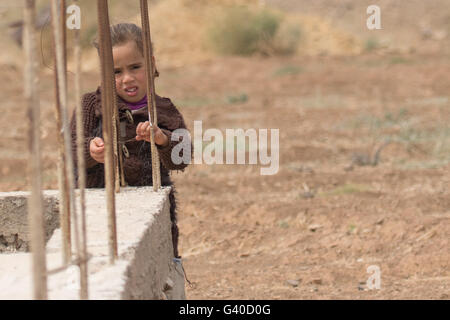 Marocaine peeping à travers les barres au post de béton, à la curieuse. Banque D'Images